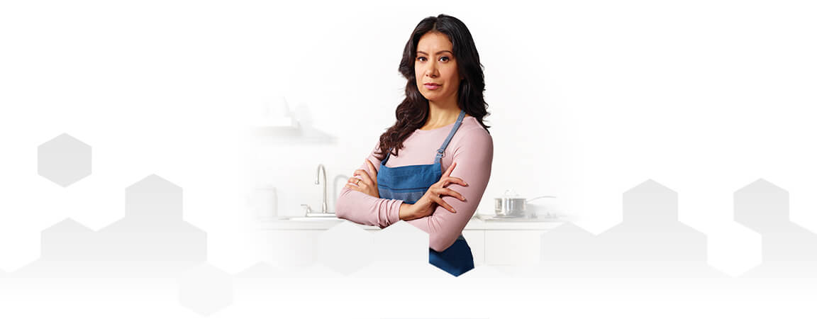 Una mamma che indossa un grembiule in piedi davanti a un bancone della cucina con le braccia incrociate